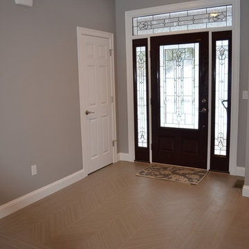 Transitional New Constrn. Entry way brown floors w/ dark wood front door