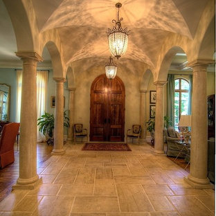 Entryway - small mediterranean limestone floor entryway idea in Atlanta with yellow walls and a medium wood front door