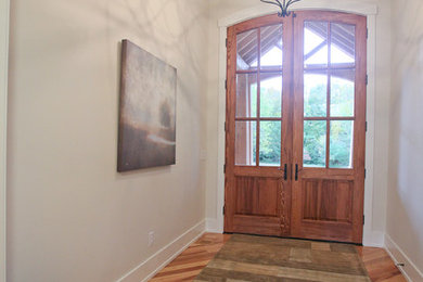 Diseño de distribuidor de estilo americano con paredes beige, suelo de madera clara, puerta doble y puerta de madera en tonos medios