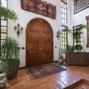 Esempio di un ingresso mediterraneo di medie dimensioni con pareti bianche, pavimento in terracotta, una porta a due ante e una porta in legno scuro