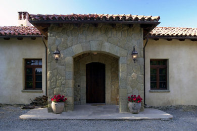 Große Mediterrane Haustür mit beiger Wandfarbe, Betonboden, Einzeltür und dunkler Holzhaustür in Santa Barbara