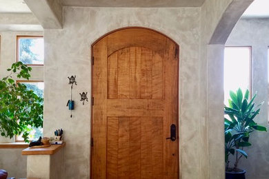 Example of a small tuscan brown floor and concrete floor entryway design in Other with beige walls and a medium wood front door