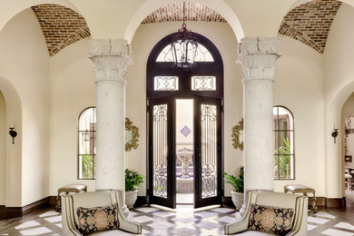 フェニックスにある広い地中海スタイルのおしゃれな玄関 (ベージュの壁、ガラスドア、マルチカラーの床) の写真