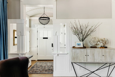 Imagen de distribuidor de estilo americano de tamaño medio con paredes beige, suelo de madera en tonos medios, puerta simple, puerta blanca y suelo marrón