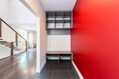 На фото: фойе среднего размера в стиле модернизм с красными стенами, полом из керамогранита, одностворчатой входной дверью, белой входной дверью и серым полом