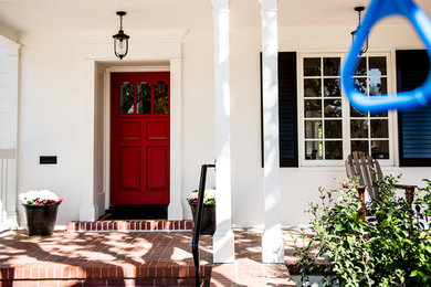 Diseño de entrada tradicional de tamaño medio con paredes blancas, suelo de ladrillo, puerta simple, puerta roja y suelo rojo