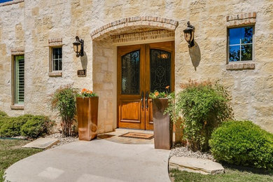 Idée de décoration pour une grande porte d'entrée méditerranéenne avec une porte double et une porte en bois brun.