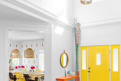 Réalisation d'un grand hall d'entrée design avec un mur blanc, un sol en bois brun, une porte simple et une porte jaune.