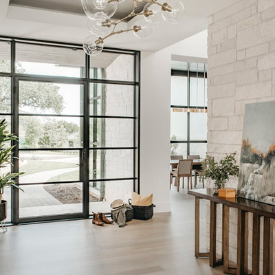 Entryway - large contemporary light wood floor entryway idea in Austin with white walls and a glass front door