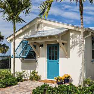 Ejemplo de puerta principal tropical con puerta simple y puerta azul