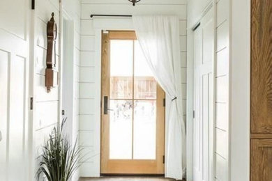 На фото: фойе среднего размера в стиле кантри с белыми стенами, светлым паркетным полом, поворотной входной дверью, входной дверью из светлого дерева и коричневым полом с