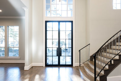 ダラスにある広いトランジショナルスタイルのおしゃれな玄関ドア (ベージュの壁、無垢フローリング、黒いドア、茶色い床) の写真