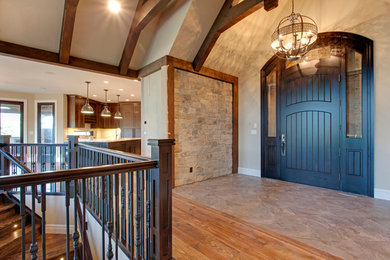 Réalisation d'un hall d'entrée chalet avec un mur beige, un sol en bois brun, une porte simple et une porte noire.