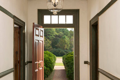 Imagen de hall tradicional con paredes beige, suelo de madera en tonos medios, puerta simple y puerta de madera oscura