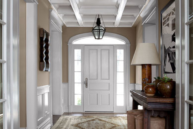 Imagen de distribuidor clásico de tamaño medio con paredes beige, suelo de madera oscura, puerta simple y puerta blanca