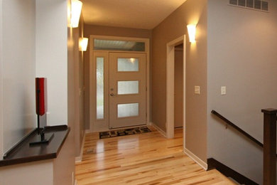 Mid-century modern light wood floor single front door photo in Omaha with gray walls and a white front door