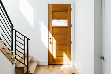 Ejemplo de distribuidor moderno de tamaño medio con paredes blancas, suelo de madera en tonos medios, puerta simple y puerta marrón