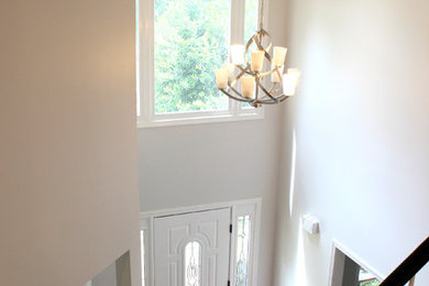 Aménagement d'un hall d'entrée moderne de taille moyenne avec un mur blanc, un sol en bois brun, une porte simple, une porte blanche et un sol beige.