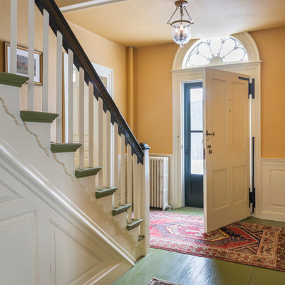 Large country painted wood floor entryway photo in Burlington with yellow walls and a white front door