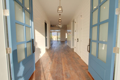 Imagen de puerta principal campestre grande con paredes blancas, suelo de madera clara, puerta doble y puerta azul
