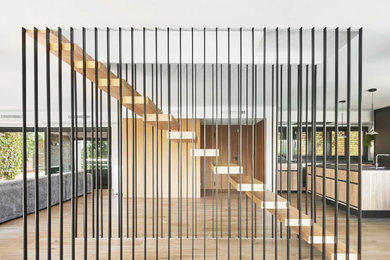 Ejemplo de escalera suspendida minimalista sin contrahuella con escalones de madera