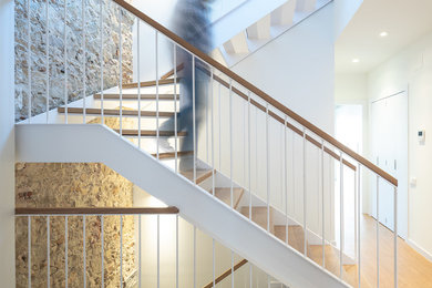 Imagen de escalera en U tradicional renovada grande sin contrahuella con escalones de madera y barandilla de metal