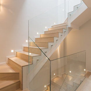 Foto de escalera en U, contemporánea, con escalones de madera, contrahuellas de madera y barandilla de vidrio