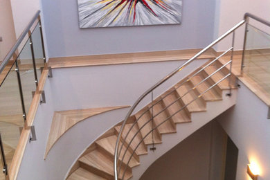 Foto de escalera curva clásica renovada de tamaño medio con escalones de madera y contrahuellas de madera