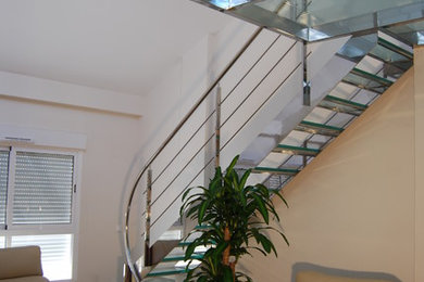 Foto de escalera en L actual de tamaño medio sin contrahuella con escalones de vidrio