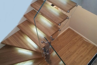 Foto de escalera en L de tamaño medio sin contrahuella con escalones de madera y barandilla de vidrio