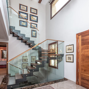 Imagen de escalera contemporánea, sin contrahuella, con escalones de madera y barandilla de vidrio