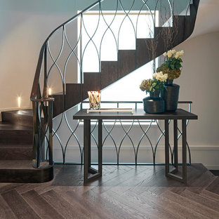 Modelo de escalera curva, actual, con escalones de madera, contrahuellas de madera y barandilla de varios materiales