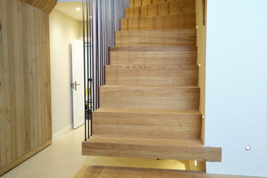 Diseño de escalera suspendida escandinava grande con escalones de madera, contrahuellas de madera y barandilla de metal