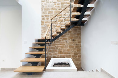 Foto de escalera en U mediterránea de tamaño medio sin contrahuella con escalones de madera y barandilla de metal