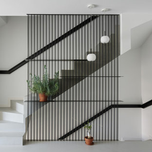 Imagen de escalera recta, actual, de tamaño medio, con escalones de hormigón, contrahuellas de hormigón y barandilla de metal