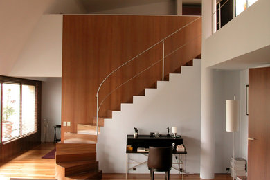 Idée de décoration pour un grand escalier courbe minimaliste avec des marches en bois, des contremarches en bois et éclairage.