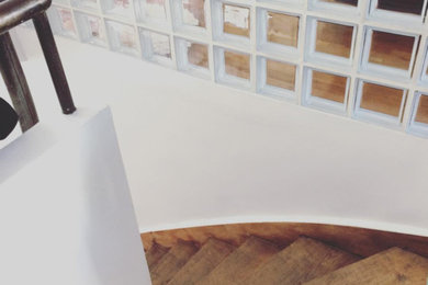 Réalisation d'un escalier courbe minimaliste avec des contremarches en bois et un garde-corps en métal.