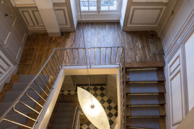 Idée de décoration pour un très grand escalier tradition avec des marches en bois, des contremarches en bois et un garde-corps en métal.