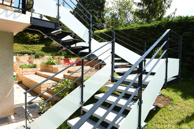 Ejemplo de escalera en U urbana grande con escalones de metal y barandilla de vidrio