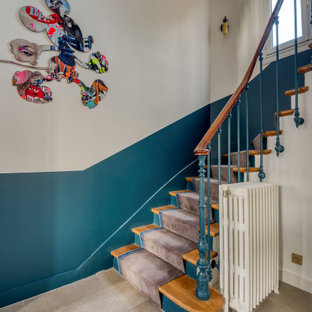 Modelo de escalera curva, ecléctica, con escalones de madera, contrahuellas de madera pintada y barandilla de varios materiales