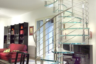 Cette image montre un petit escalier sans contremarche hélicoïdal design avec des marches en verre et un garde-corps en métal.