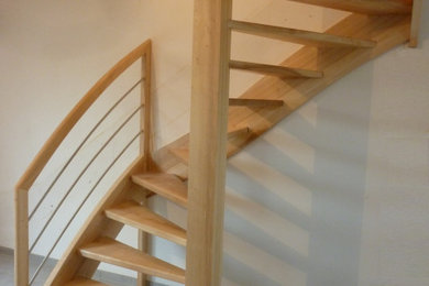 Réalisation d'un petit escalier hélicoïdal design avec des marches en bois et un garde-corps en métal.