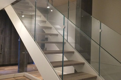 Diseño de escalera recta actual grande con escalones de madera y barandilla de vidrio