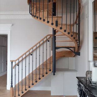 Exemple d'un escalier hélicoïdal chic de taille moyenne avec des marches en bois, un garde-corps en matériaux mixtes et des contremarches en bois.