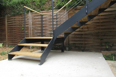 Réalisation d'un escalier courbe urbain de taille moyenne avec des marches en bois et un garde-corps en câble.