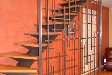 Cette image montre un escalier courbe minimaliste de taille moyenne avec des marches en bois et un garde-corps en métal.