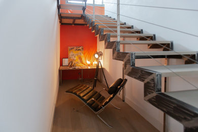 Aménagement d'un grand escalier courbe moderne avec des marches en bois et un garde-corps en métal.