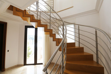 Ejemplo de escalera curva minimalista con escalones de madera y contrahuellas de madera