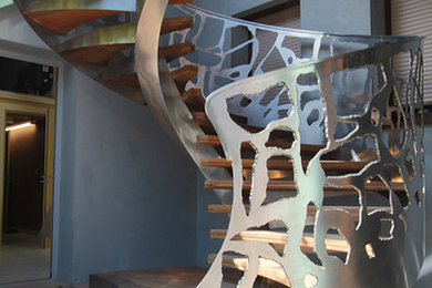 Idées déco pour un grand escalier courbe contemporain avec des marches en bois et un garde-corps en métal.