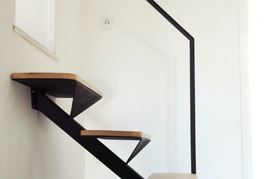 Cette photo montre un escalier courbe tendance avec des marches en bois, des contremarches en métal et un garde-corps en métal.